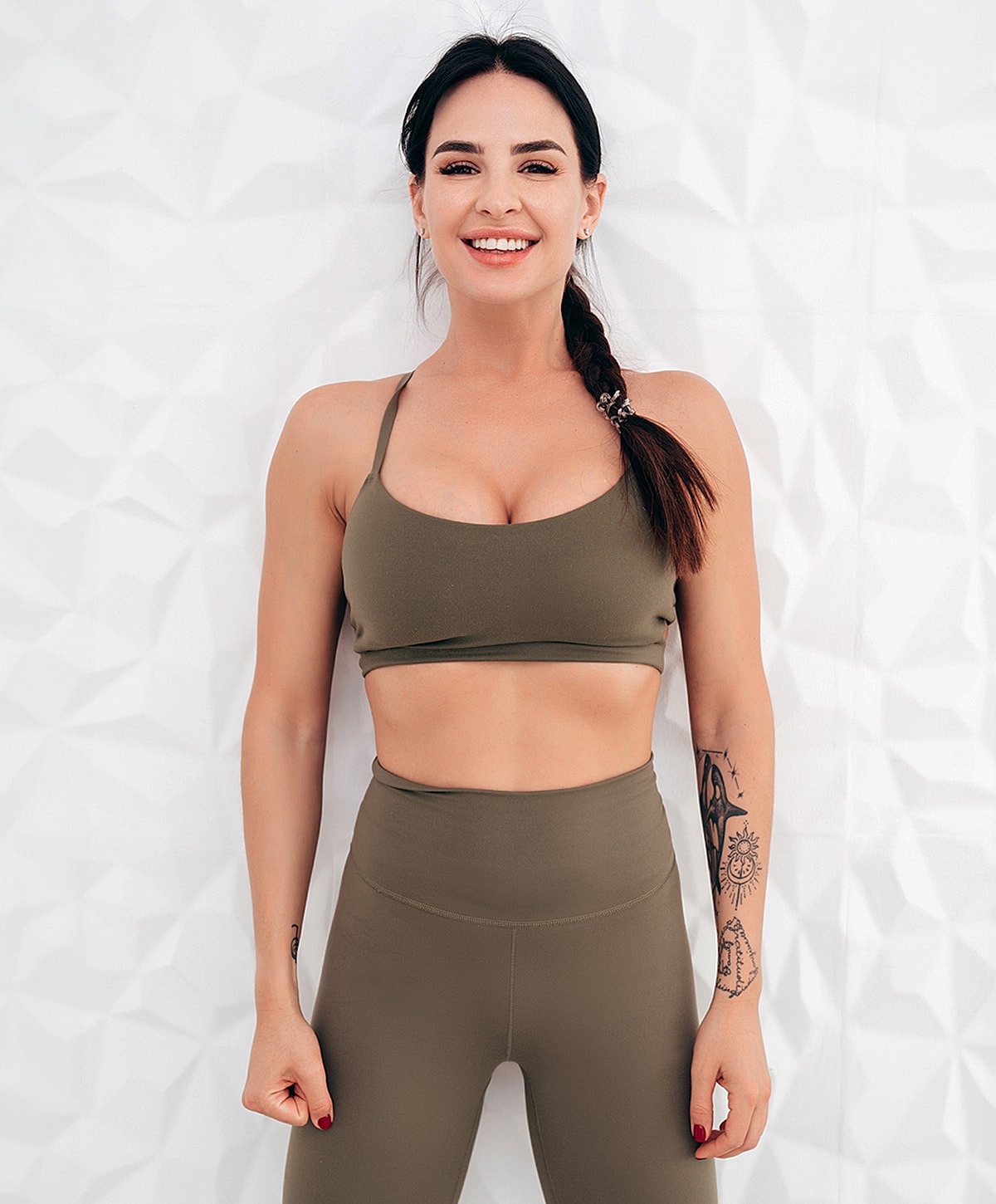 Smiling woman in athletic wear against textured background.
