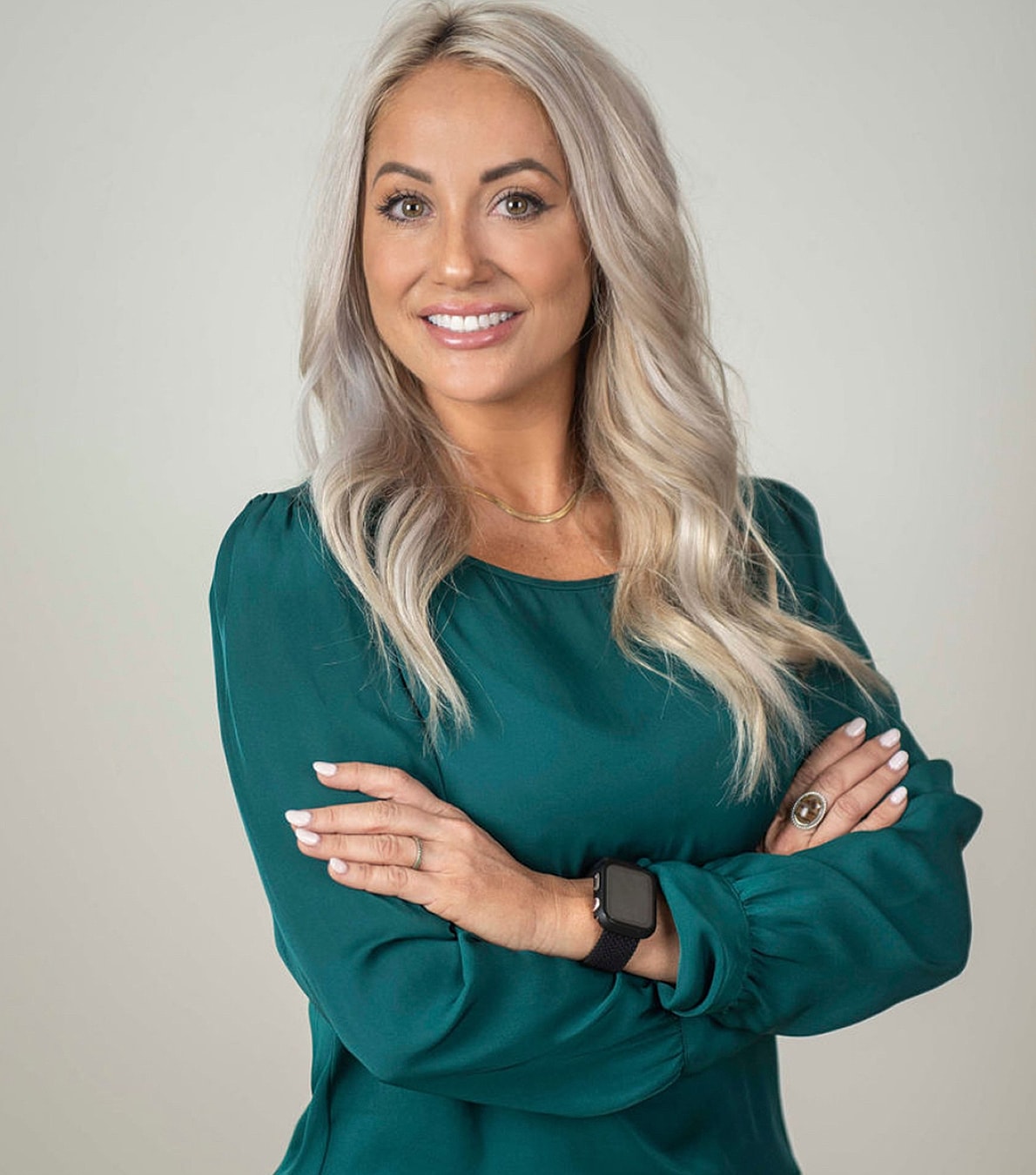 Smiling woman in green blouse with arms crossed.