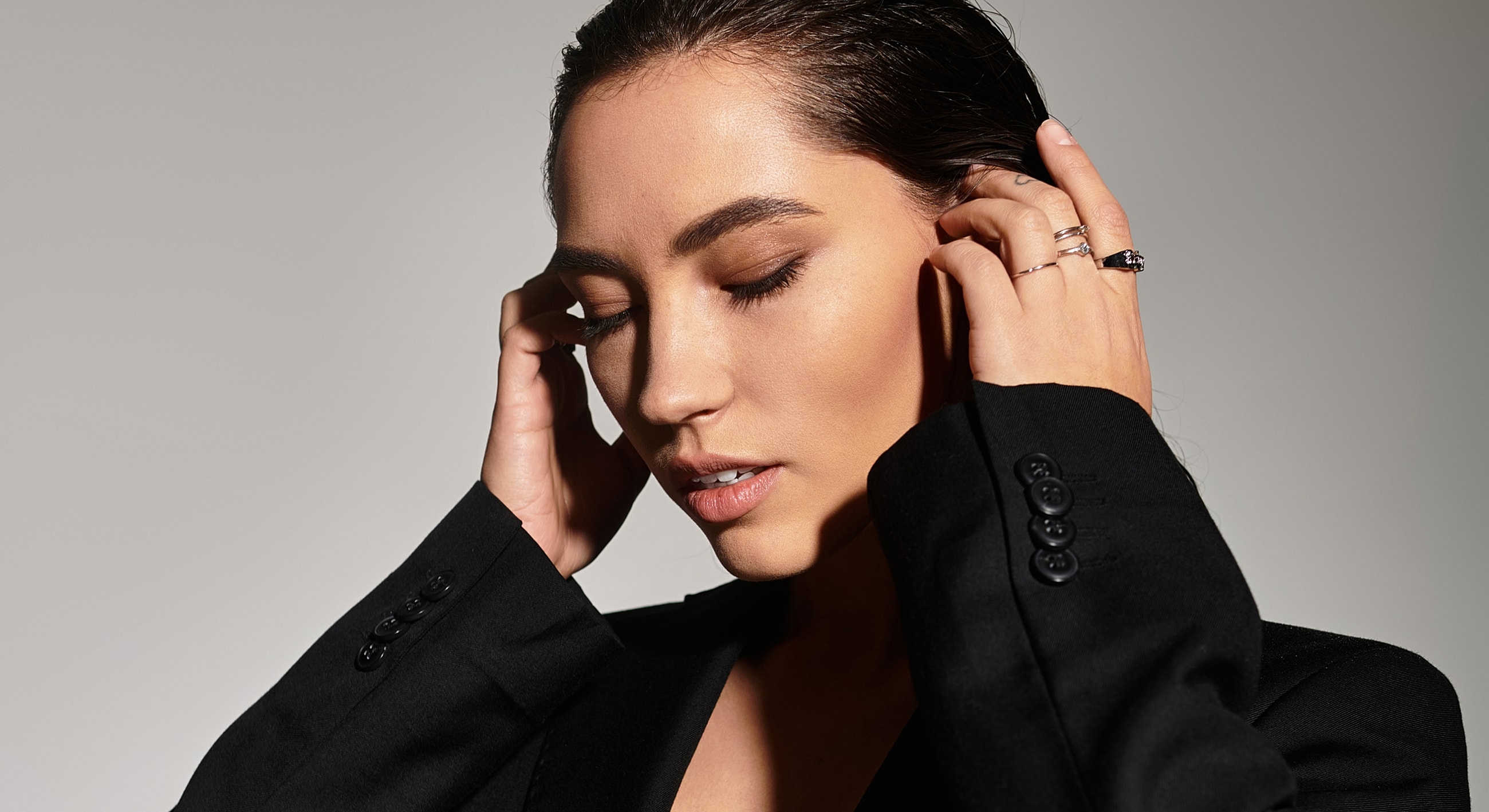 Woman in black blazer with closed eyes.