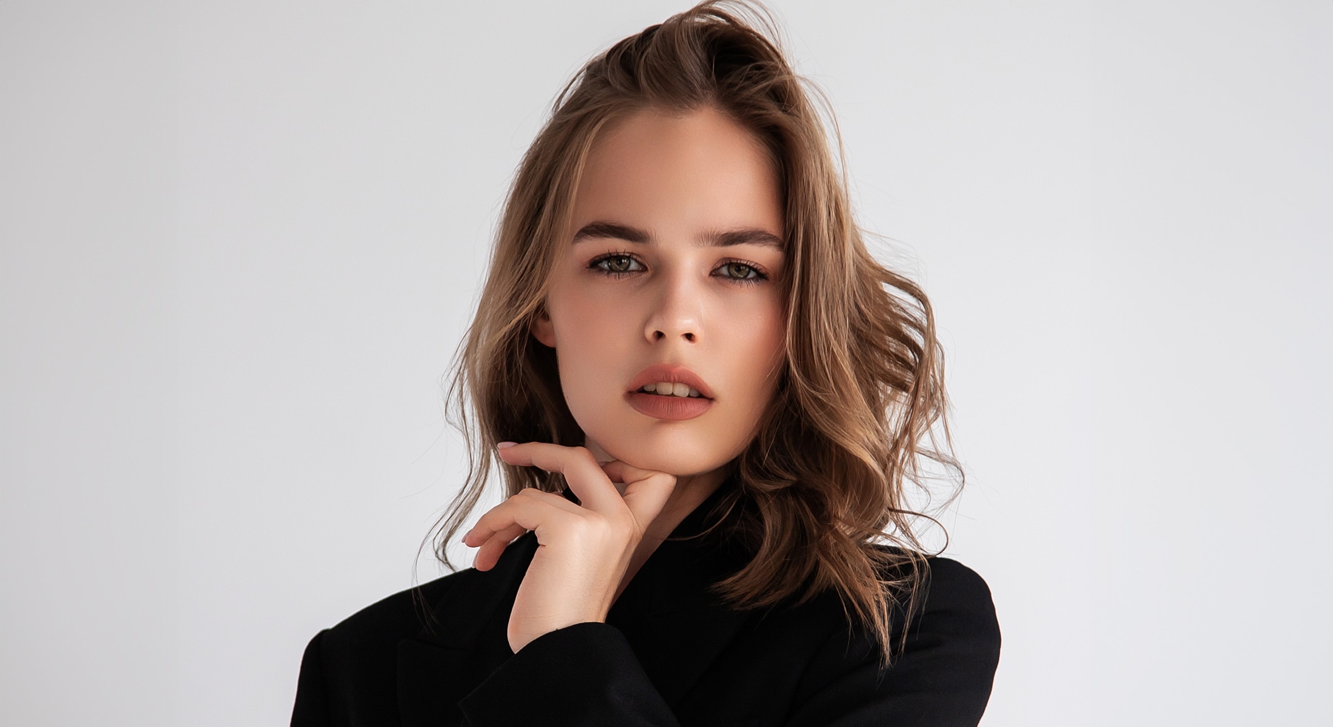 Woman in black blazer with thoughtful expression.
