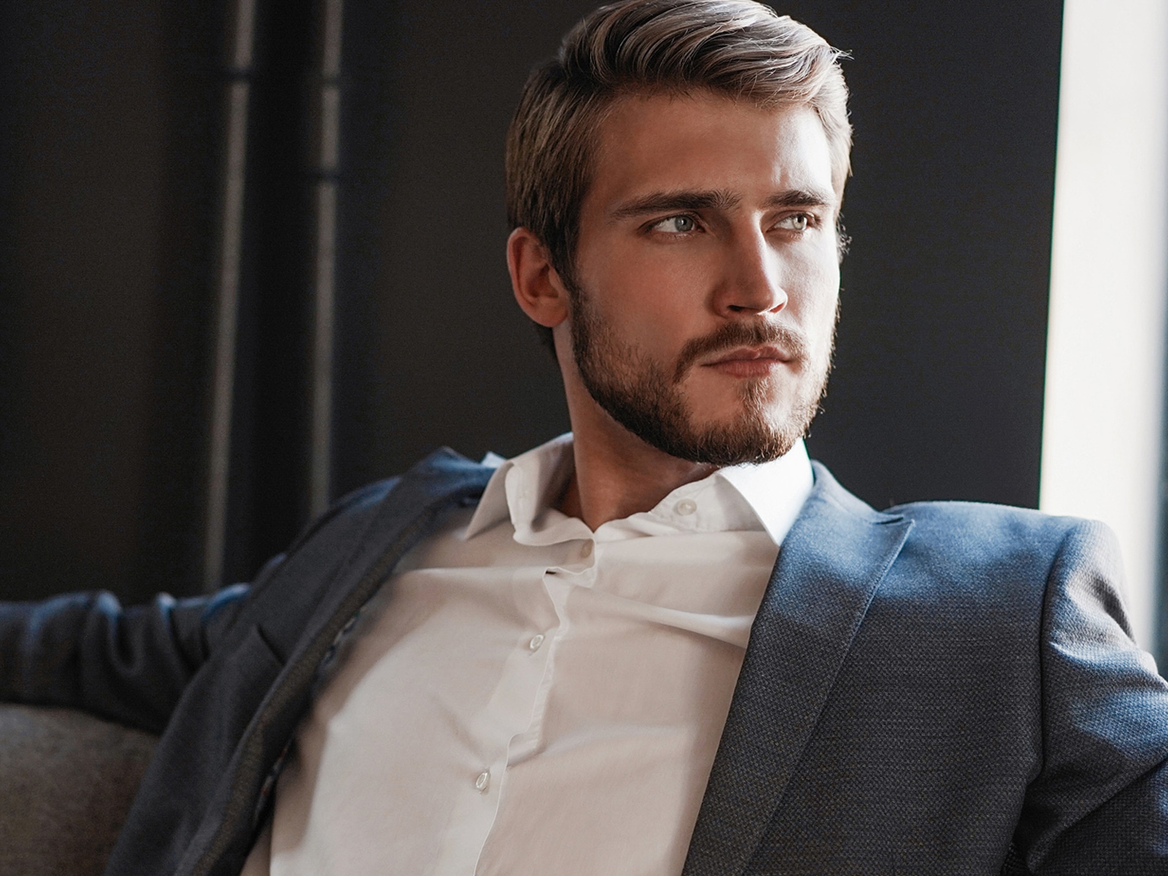 Stylish man in suit contemplating thoughtfully.